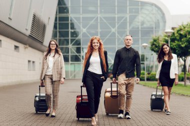 Ön manzara, mutlu genç insanlar, üç kadın ve havaalanı yakınlarında bagajlı bir adam. Seyahatten dönen arkadaşlar. Seyahat ve tatil kavramı