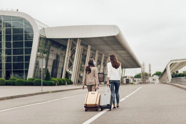 Figur-figur bergambar wanita muda bertopeng pelindung pergi ke bandara dengan koper. Aman perjalanan selama pandemi — Stok Foto