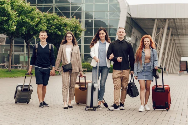 Happy positif orang-orang muda dengan bagasi luar dekat bandara. Teman kembali dari perjalanan. Konsep perjalanan dan liburan — Stok Foto