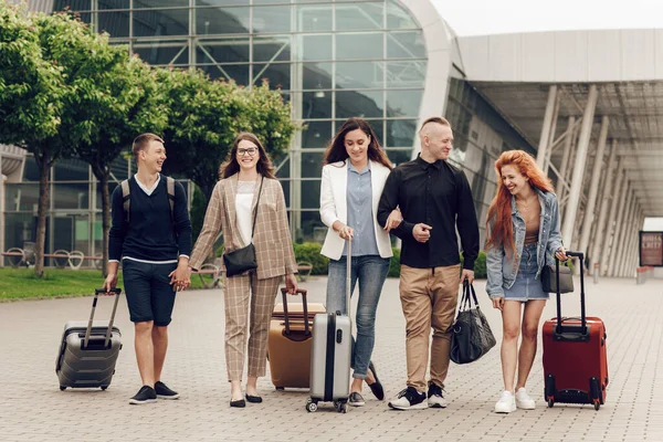 Happy positif orang-orang muda dengan bagasi luar dekat bandara. Teman kembali dari perjalanan. Konsep perjalanan dan liburan — Stok Foto