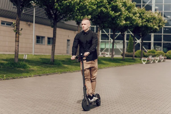 Den unge mannen kör en elskoter runt i stan. Det senaste teknikkonceptet, utvecklingen av vetenskap och teknik — Stockfoto