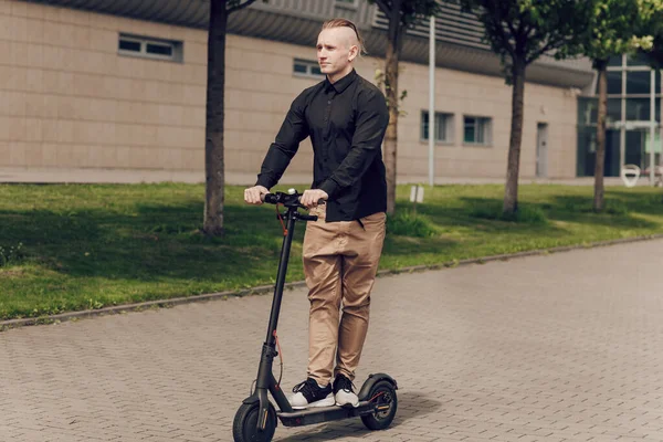 Den unge mannen kör en elskoter runt i stan. Det senaste teknikkonceptet, utvecklingen av vetenskap och teknik — Stockfoto