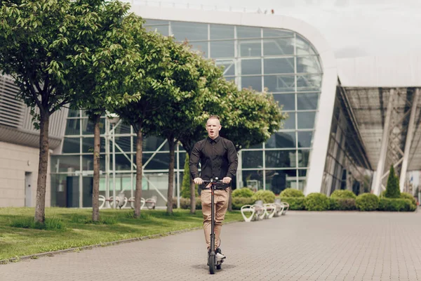 Den unge mannen kör en elskoter runt i stan. Det senaste teknikkonceptet, utvecklingen av vetenskap och teknik — Stockfoto