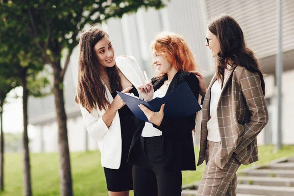 Bekerja di luar kantor. Tiga pengusaha Kaukasia sukses berjas berdiri di jalan untuk membahas bisnis. Wanita muda melihat dokumen, berbicara satu sama lain — Stok Foto