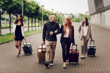 Ön manzara, mutlu genç insanlar, üç kadın ve havaalanı yakınlarında bagajlı bir adam..