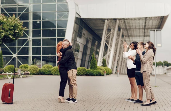 Pasangan romantis berdiri di dekat bandara dengan sebuah koper. Pria tampan membuat penawaran kepada wanita mudanya — Stok Foto