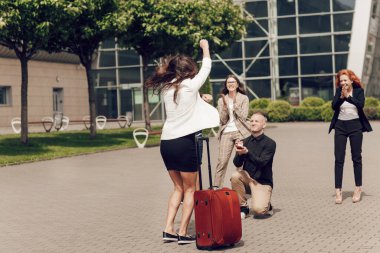Havaalanının yanında bavulla bekleyen romantik bir çift. Adam çekici, genç, esmer kadınına teklifte bulunuyor.