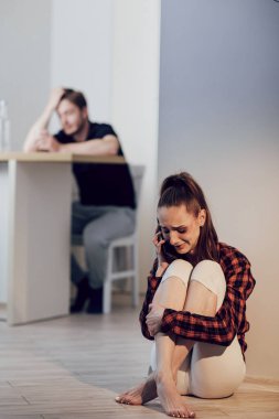 Yüzünde morluklar olan genç ve korkmuş bir kadın kocasından saklanıyor ve polisi arıyor. Mutfakta alkol alan sarhoş bir adam. Aile içi şiddet ve alkolizm kavramı