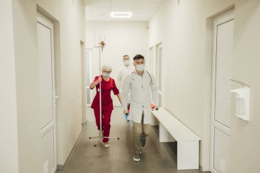 Bir doktor ekibi hasta bir hastayı sedyeyle çabucak taşıdı. Koruyucu maskeli ve takım elbiseli ambulans doktorları, hasta koronavirüsten şüpheleniyor. Bir salgın sırasında sağlık görevlilerinin çalışmaları