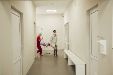 Ambulans doktorları Coronavirus hastası olan bir hastayı sedyeyle getirdiler. Koruyucu giysiler içindeki doktorlar hastayı hastaneye götürürler. Koronavirüs salgını, zatürree.