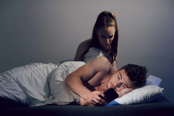 The concept of relationships and betrayal in the family. The man, lying in bed, corresponded on mobile phone with his mistress. The wife woke up and watching her husband