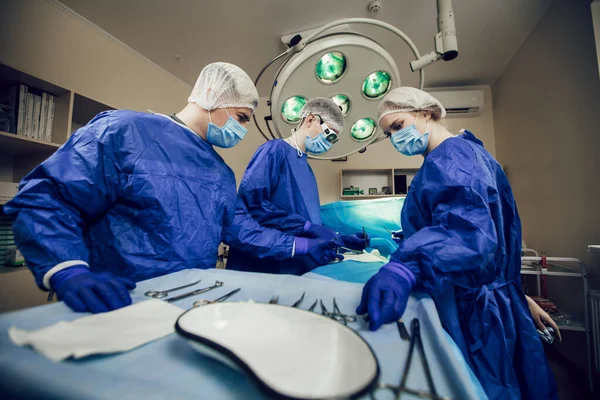 Portret van een team chirurgen aan het werk. Drie dokters in medische maskers bij operaties beginnen de patiënt te opereren. Artsen in chirurgie, behandeling en geneeskunde — Stockfoto