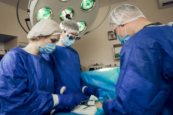 Potret tim ahli bedah di tempat kerja. Tiga dokter bertopeng medis dalam operasi mulai mengoperasi pasien.. — Stok Foto