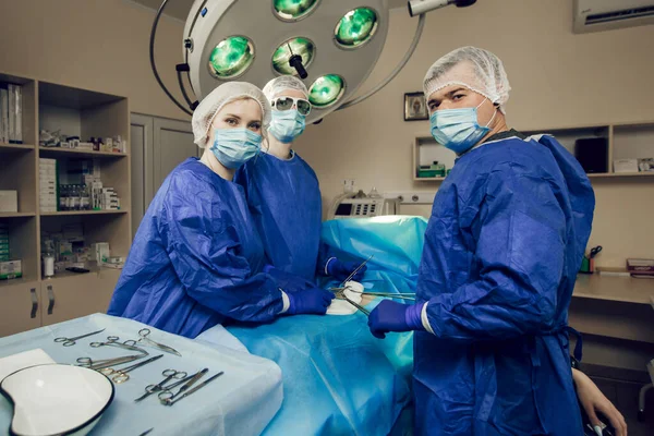 Potret tiga ahli bedah di tempat kerja. Dokter sedang mempersiapkan operasi. Ahli bedah dan pasien di rumah sakit — Stok Foto