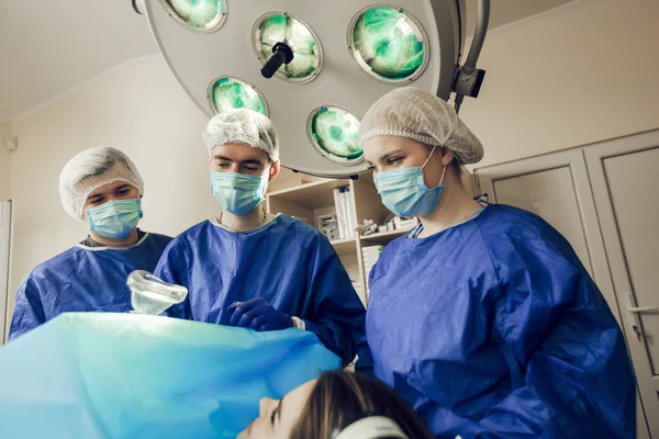 Portret van drie chirurgen aan het werk. Artsen bereiden zich voor op de operatie. Chirurgen en een patiënt in het ziekenhuis — Stockfoto