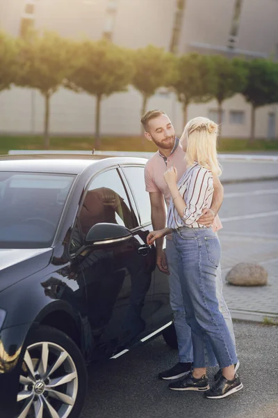 행복 한 젊은 남녀가 새 차를 산다. 야외에서 차를 구입하는 모습 — 스톡 사진