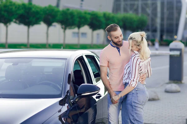 Szczęśliwa młoda para, mężczyzna i kobieta, kupcie nowy samochód. Kupowanie samochodu na zewnątrz — Zdjęcie stockowe