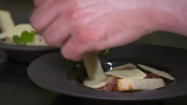 The hand of a chef who prepares a dish with a grastronomic egg, before serving his customers in the restaurant. Restaurant, food, quality, nature, gastronomy, gourmet concept.