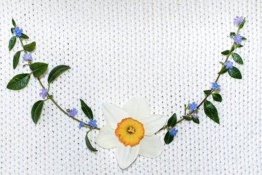 Yeşil dal, çiçek irili ufaklı bir arka planda örme kumaş.