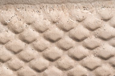 Tekerlek izleme yol yapımı sırasında kahverengi kum yüzeylerde. Dokulu lastik üzerinde ıslak kum portre izler. Endüstriyel arka plan. Nervürlü diziniz tekerlek koruyucular.