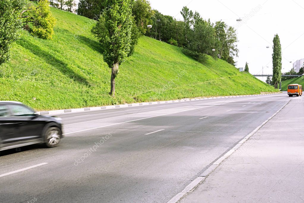 A bright orange bus is moving along an empty road