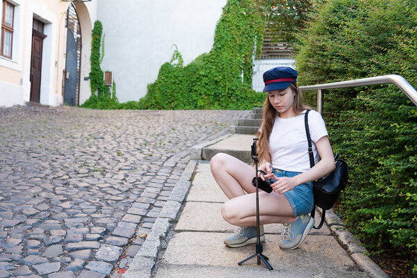 Девушка-фотограф готовится фотографировать на улице