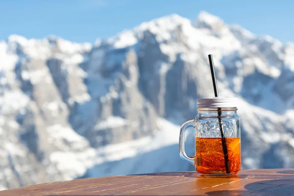 Mok aperol staat op de tafel van een straat café tegen de achtergrond van de bergen. — Stockfoto