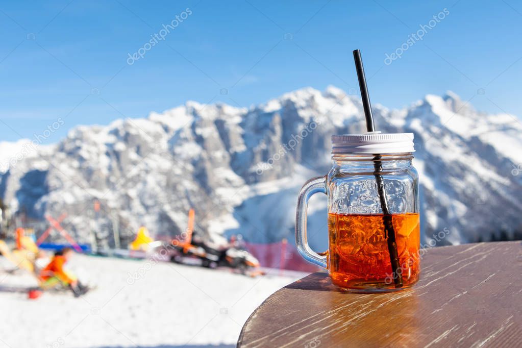 Mug aperol stands on the table of the street cafe on the slope of the ski resort.