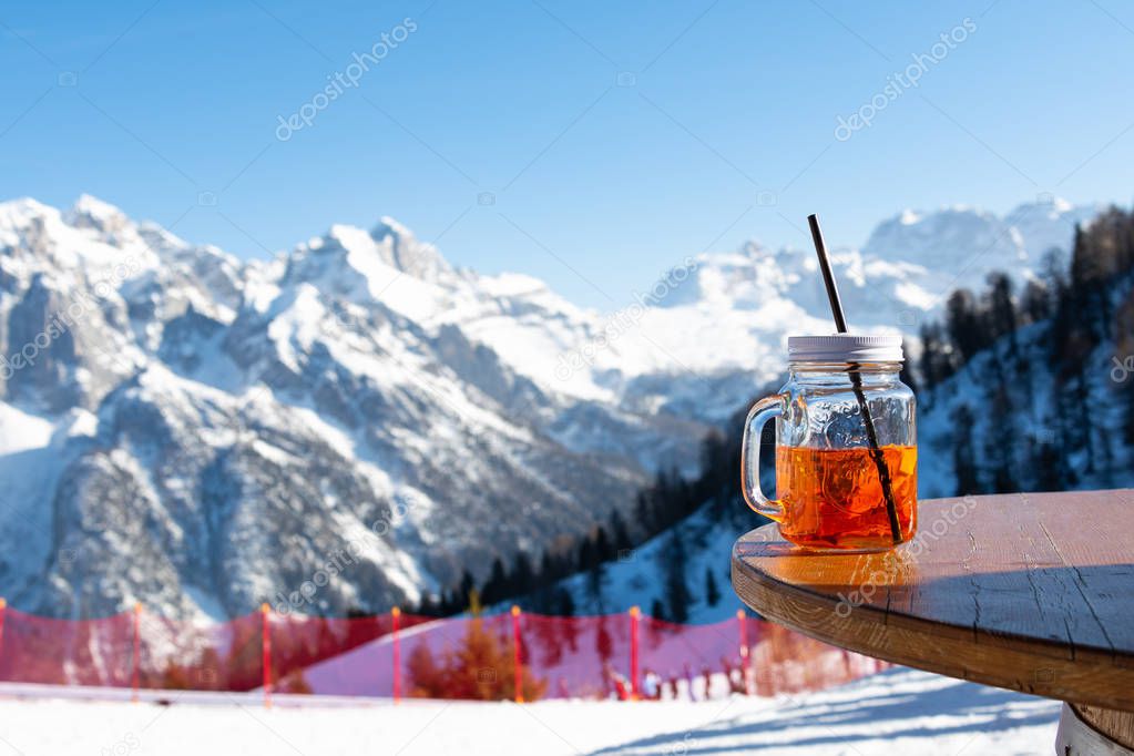 Mug aperol stands on the table of a street cafe against the backdrop of the mountains.
