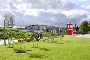 Lila çalılar ve parlak kırmızı Zaryadye Park'ta bina ile su kuyusu-damat bir çim görünümünü.