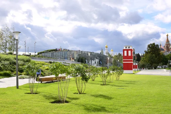 Lila çalılar ve parlak kırmızı Zaryadye Park'ta bina ile su kuyusu-damat bir çim görünümünü.