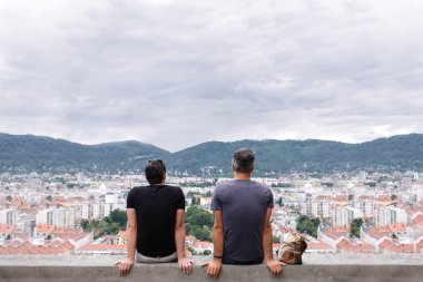 İki adam yüksek bir binanın kenarında oturup dağlara mesafe içine bakmak.