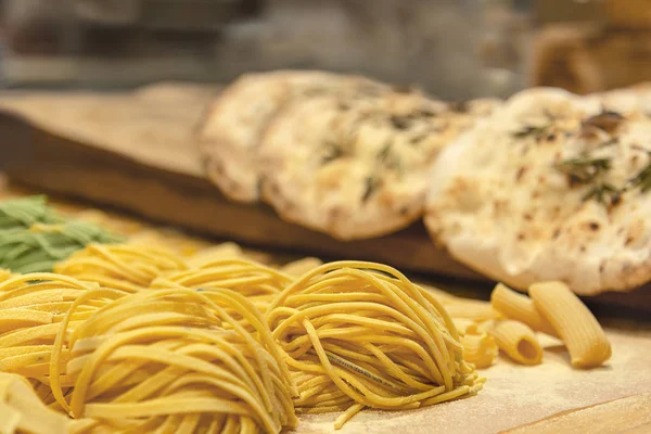 Fresh uncooked homemade wheat pasta is rolled up on the table against the background of chiabat.