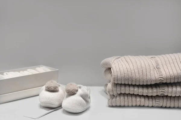 Babystiefel, Pullover und Socken aus natürlichen beigen Stoffen liegen auf dem Tisch. — Stockfoto