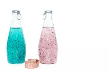 Beyaz arka plan üzerinde mavi ve pembe fesleğen tohumu standı ile bir santimetre ve cam şişeler.