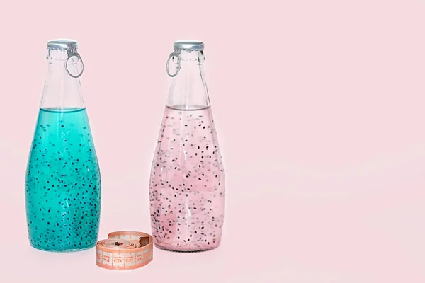 Сантиметр і скляні пляшки з синьо-рожевим насінням базиліка стоять на рожевому фоні . — стокове фото
