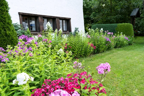 Blick auf den gepflegten Garten mit grünem Rasen, Blumen und Bäumen in Hausnähe. — Stockfoto