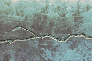 Gri beton duvar dokusu mavi sıva ve derin çatlak ile dekore.