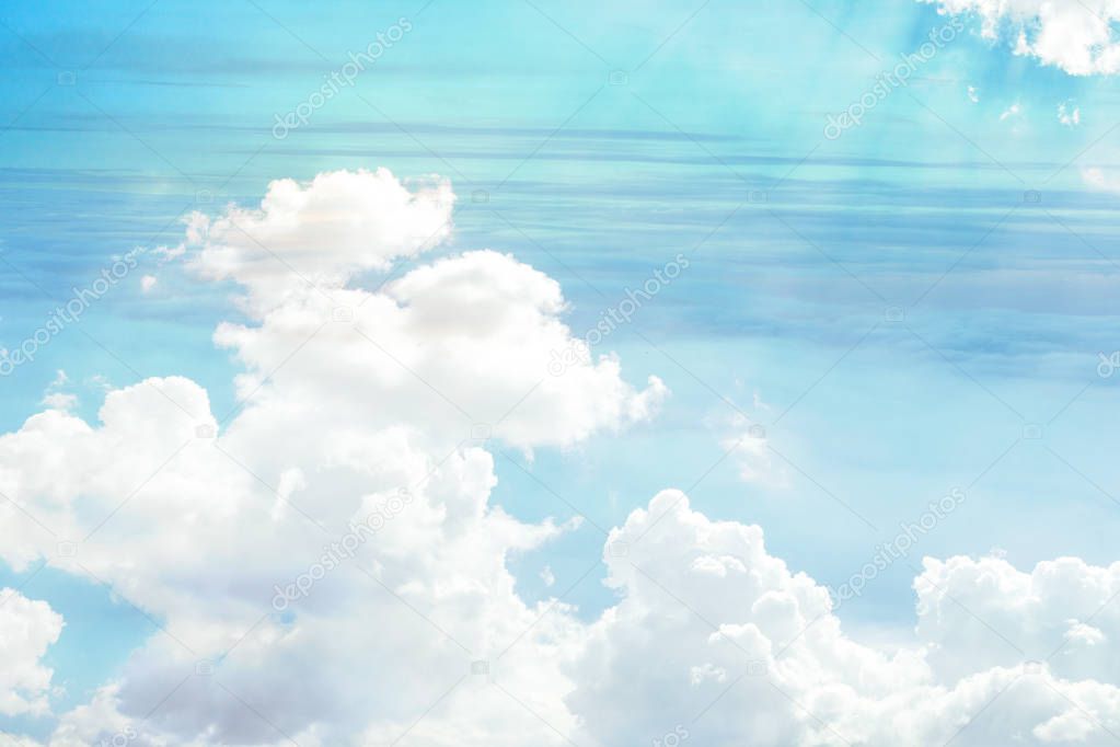 The view of the sky is turquoise in color and white clouds through which the suns rays penetrate.