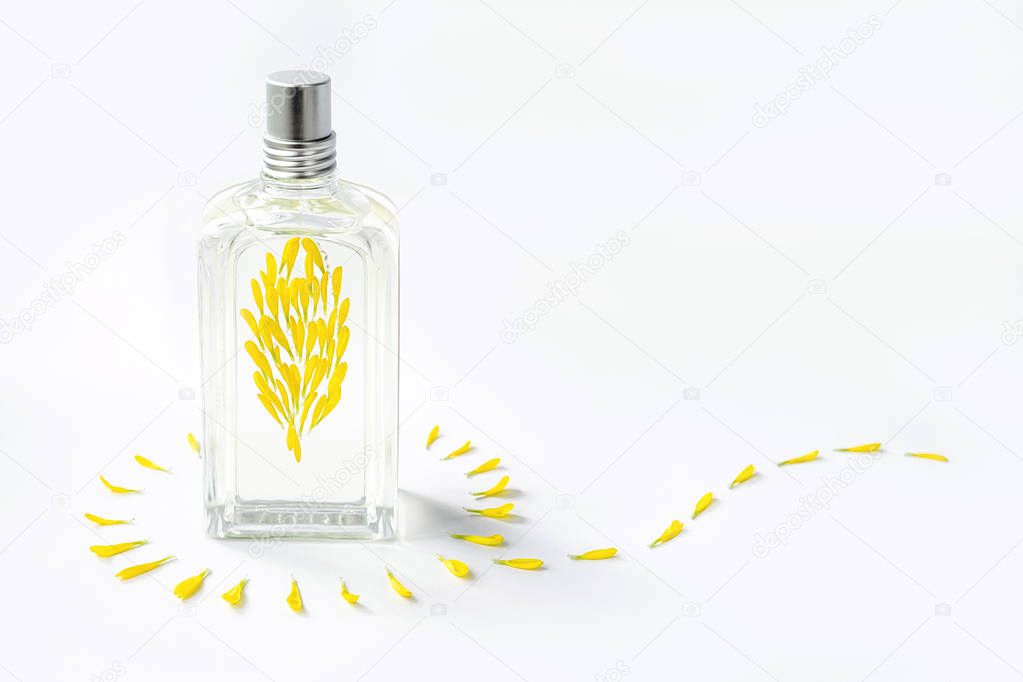 Transparent perfume bottle on a white background decorated with yellow flower petals