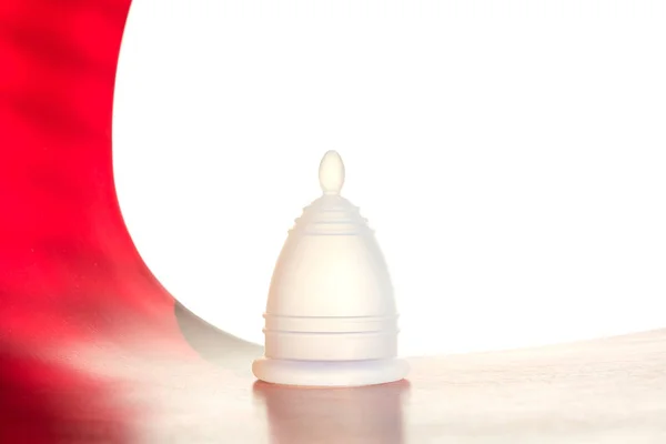 Witte herbruikbare menstruele Cup op een wit-rode achtergrond. — Stockfoto