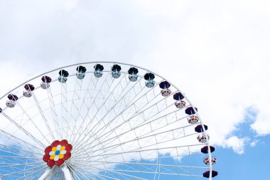 Mavi gökyüzü ve beyaz bulutların arka planına karşı dönme dolap görünümü. Eğlence konsepti.