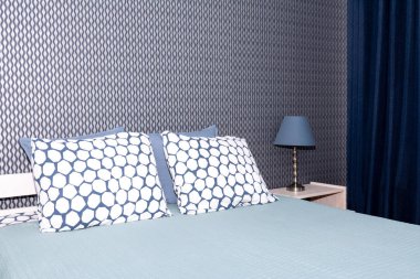 Bir çift kişilik yatak ile yatak odası karanlık bir duvara karşı bir lamba ve mavi bir perde ile bir komandite. Ev, tatil konsepti.