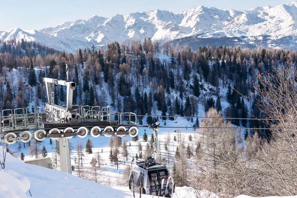 The metal structure of the cableway against the backdrop of snow-capped mountains of the Dolomites in the ski resort. — Stock Photo, Image