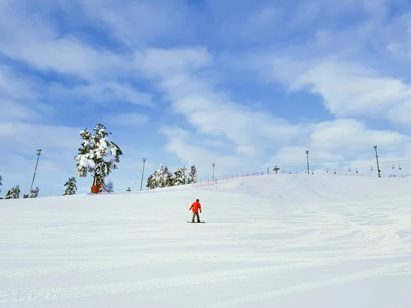 Un snowboarder descend une pente de montagne sur fond de ciel couvert de nuages . — Photo