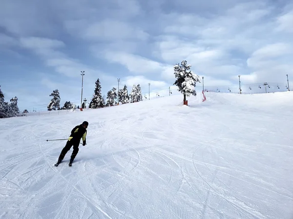 Ein Skifahrer rutscht vor dem Hintergrund eines wolkenverhangenen Himmels einen Berghang hinunter. — Stockfoto
