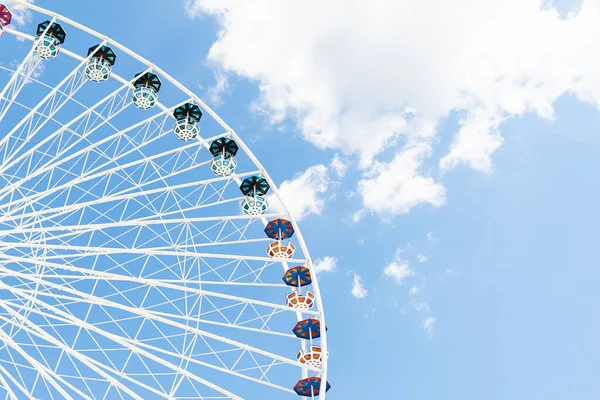 A ferris wheel of white color with multi-colored cabins against the blue sky. — Stock Photo, Image