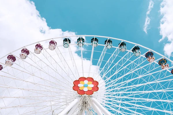 A ferris wheel of white color with multi-colored cabins against the blue sky. — Stock Photo, Image