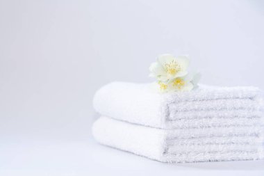 Arkaplanda yasemin çiçeği olan iki beyaz terry havlusu.