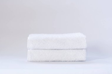 Aydınlık bir arkaplanda iki beyaz terry havlu.